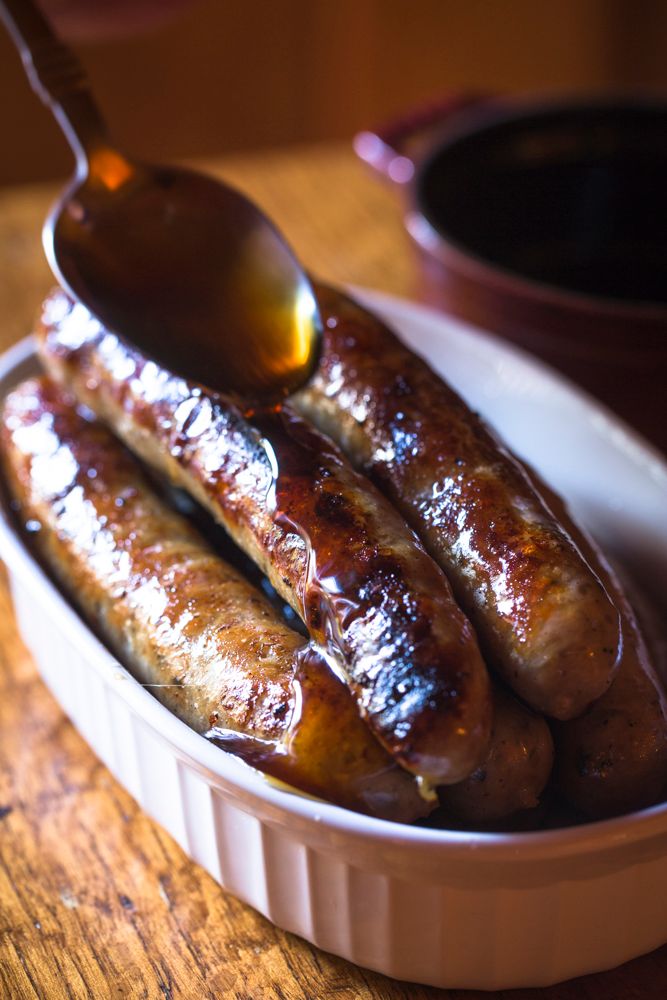 a dish of brekfast sausages in a dish being glazed with honey on a rustic table