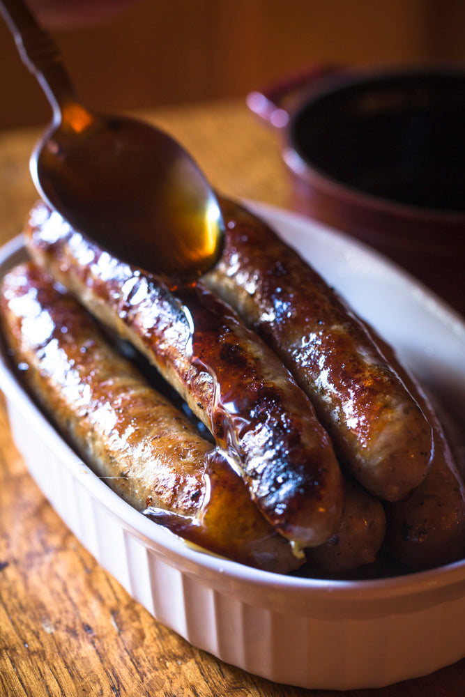 brekfast sausages in a dish being glazed in honey