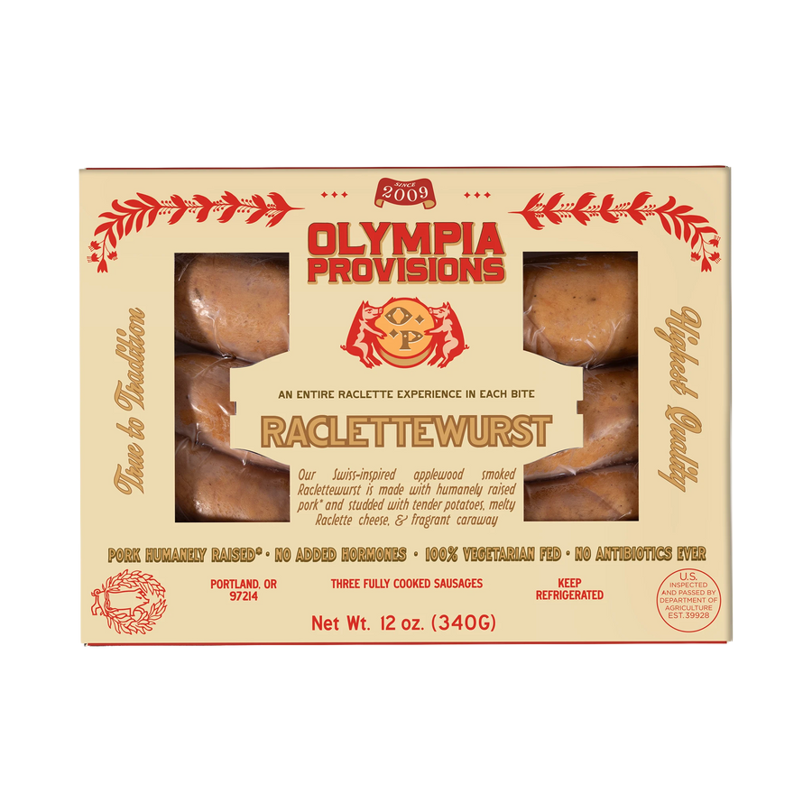 Three links of Olympia Provisions Raclettewurst sausage in cream packaging.