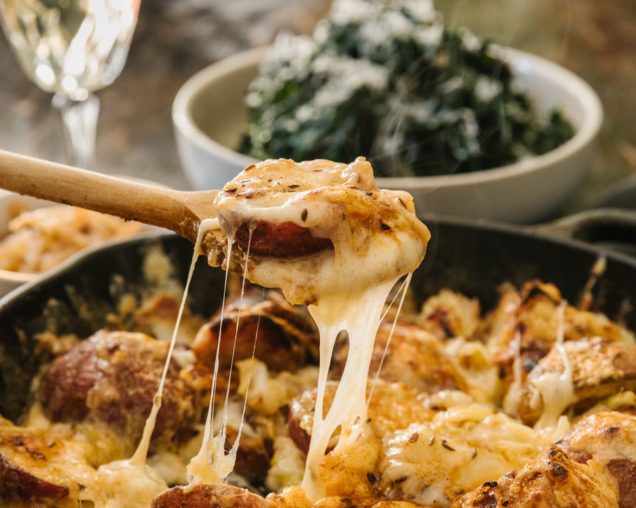 Spoonful of raclette one pan dish being served, very melty cheese